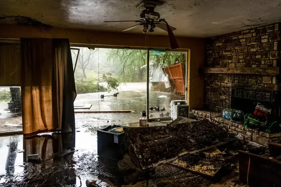 Muddy water and scattered debris covering a flooded living room floor